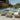 Outdoor patio furniture set with beige cushions and blue pillows by a pool.