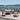 Outdoor furniture set on a wooden deck with a scenic view of water and mountains.