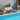 Outdoor patio set with sofa, chairs, and table by a poolside.