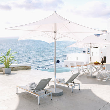 Grand Patio 11 ft sunshade umbrella with a white canopy, positioned near lounge chairs by the ocean.