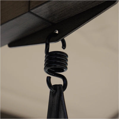 Close-up of a black metal hook with a coiled spring on a beige background