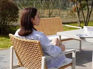 Woman sitting on a wicker chair in an outdoor setting