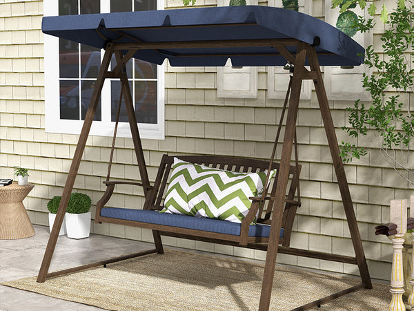 Wooden swing with blue cushion and green and white pillow on a patio