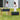 Two people standing next to two rectangular planters with flowers on a grassy area.