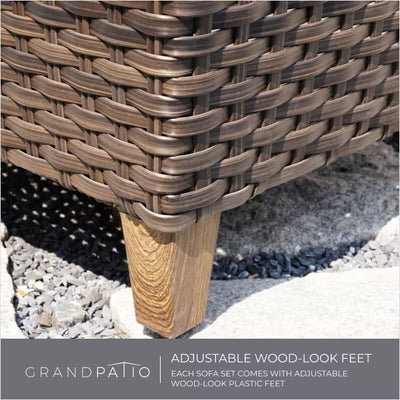 Close-up of a woven outdoor sofa with adjustable wood-look feet on a gravel surface, featuring Grand Patio branding.