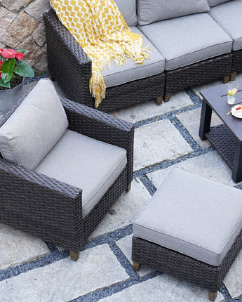 Grand Patio outdoor wicker sectional sofa set with thick gray cushions, steel frame, and a matching ottoman on stone patio.