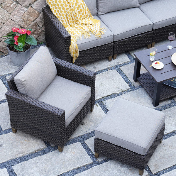 Grand Patio outdoor wicker sectional sofa set with thick gray cushions, steel frame, and a matching ottoman on stone patio.