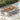 Outdoor dining set with a wooden table and chairs on a patio near a pool.