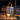 Decorative lantern with a wooden base and metal top on a wooden surface at night.