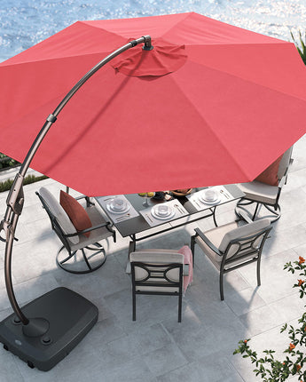Red cantilever patio umbrella with a curved pole, positioned over a dining table and chairs on a stone patio by the water.