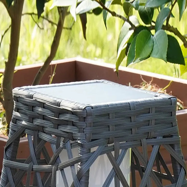 Gray woven stool with a cushioned seat in an outdoor setting