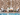 Outdoor seating area with chairs and a table against a stone wall by a pool.