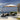 Grand Patio 11 ft cantilever patio umbrella with a beige canopy and a black base, positioned by a poolside lounge area.