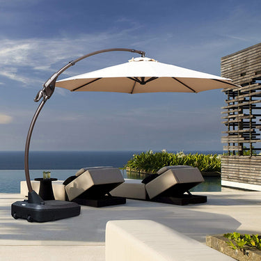 Grand Patio 11 ft cantilever patio umbrella with a beige canopy and a black base, positioned by a poolside lounge area.