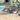 Outdoor wicker patio conversation set featuring two chairs with gray cushions and a black side table on a wooden deck.