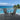 Two dark gray outdoor chairs on a wooden deck with a pool and ocean view.