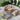 Outdoor patio furniture set with wicker chairs and a wooden table on a stone patio.