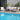 Outdoor patio furniture set by a pool with plants in the background