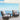 Two wicker chairs with gray cushions on a balcony with a blue ocean view.