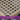 Close-up of handwoven resin wicker with a classic cane pattern on a dark background.