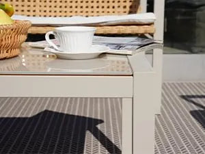 Café table with a cup of coffee, saucer, and newspaper on a metal surface.