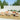 Outdoor patio furniture set with beige cushions and orange pillows on a wooden deck.
