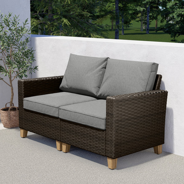 Grand Patio outdoor wicker sectional sofa with thick gray cushions and a steel frame, set on a patio with greenery.