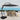 Outdoor patio set with black cantilever umbrella and table by the ocean.