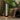 Grand Patio outdoor solar-powered crossover woven resin wicker floor lamp beside a chair and plants in a cozy setting.