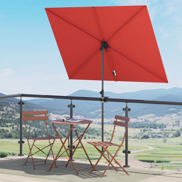 Red rectangular patio umbrella with a black pole, shading a small round table and two folding chairs on a balcony.