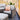 Outdoor patio furniture set with wicker chairs and ottoman on a wooden deck.