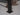 Close-up of a metal leg with a square base on a tiled floor.