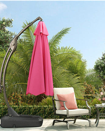 Grand Patio 11 ft cantilever patio umbrella in pink, with a sturdy base, set in a garden with greenery and outdoor furniture.