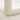 Close-up of a corner of a white cabinet with a visible leg on a light-colored floor.