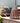 Brown woven lantern on a wooden surface with plants and furniture in the background