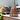 Brown woven lantern on a wooden surface with plants and furniture in the background