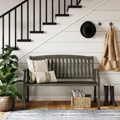 Nestled staircase with a wooden bench, plant, and coat rack in a home interior.