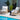 Two wooden chairs with white cushions by a poolside