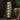 Decorative floor lamp with geometric pattern in a dimly lit room with plants and a blanket.