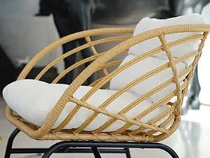 Wicker chair with white cushion on a blurred background